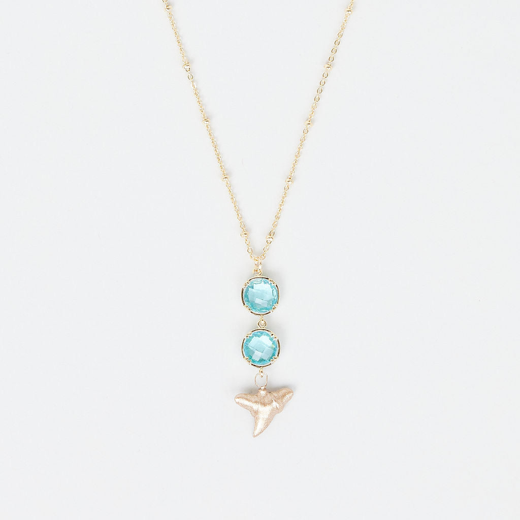 Necklace with two turquoise gemstones and a gold shark tooth pendant on a white background