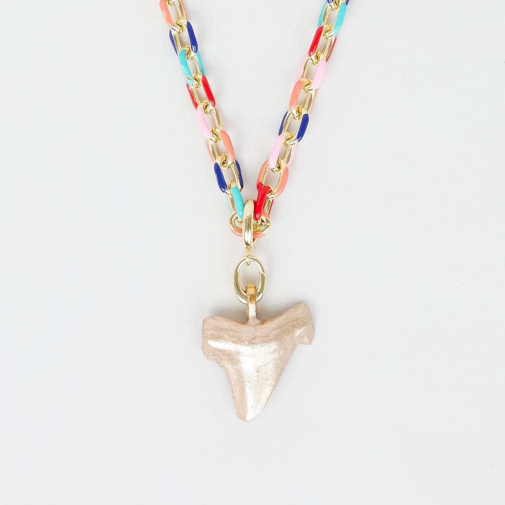 Necklace with colorful chain and shark tooth pendant on a light gray background