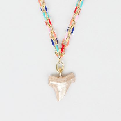 Necklace with colorful chain and shark tooth pendant on a light gray background