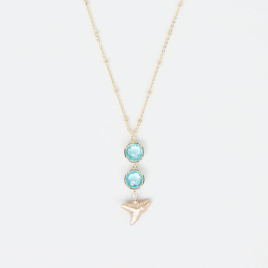 Necklace with two turquoise gemstones and a gold shark tooth pendant on a white background