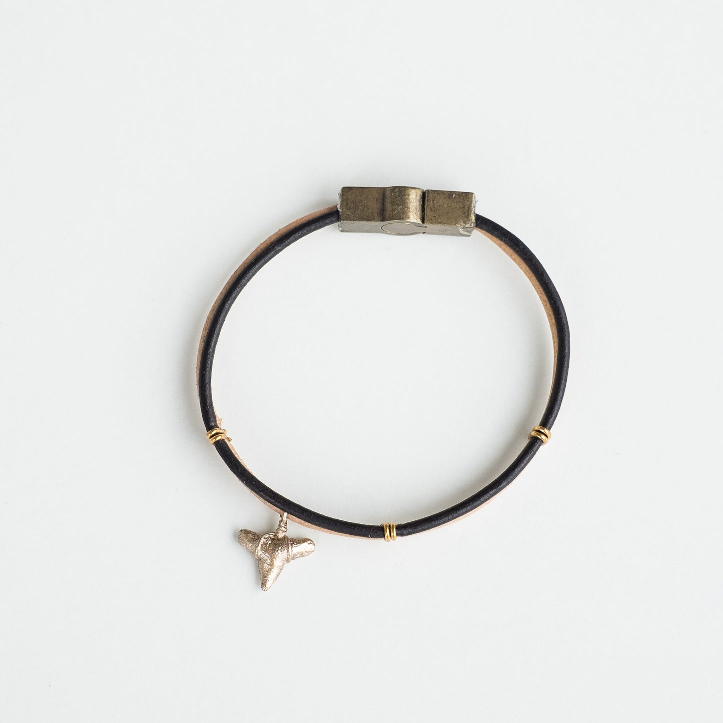 gold shark tooth bracelet on black and tan leather