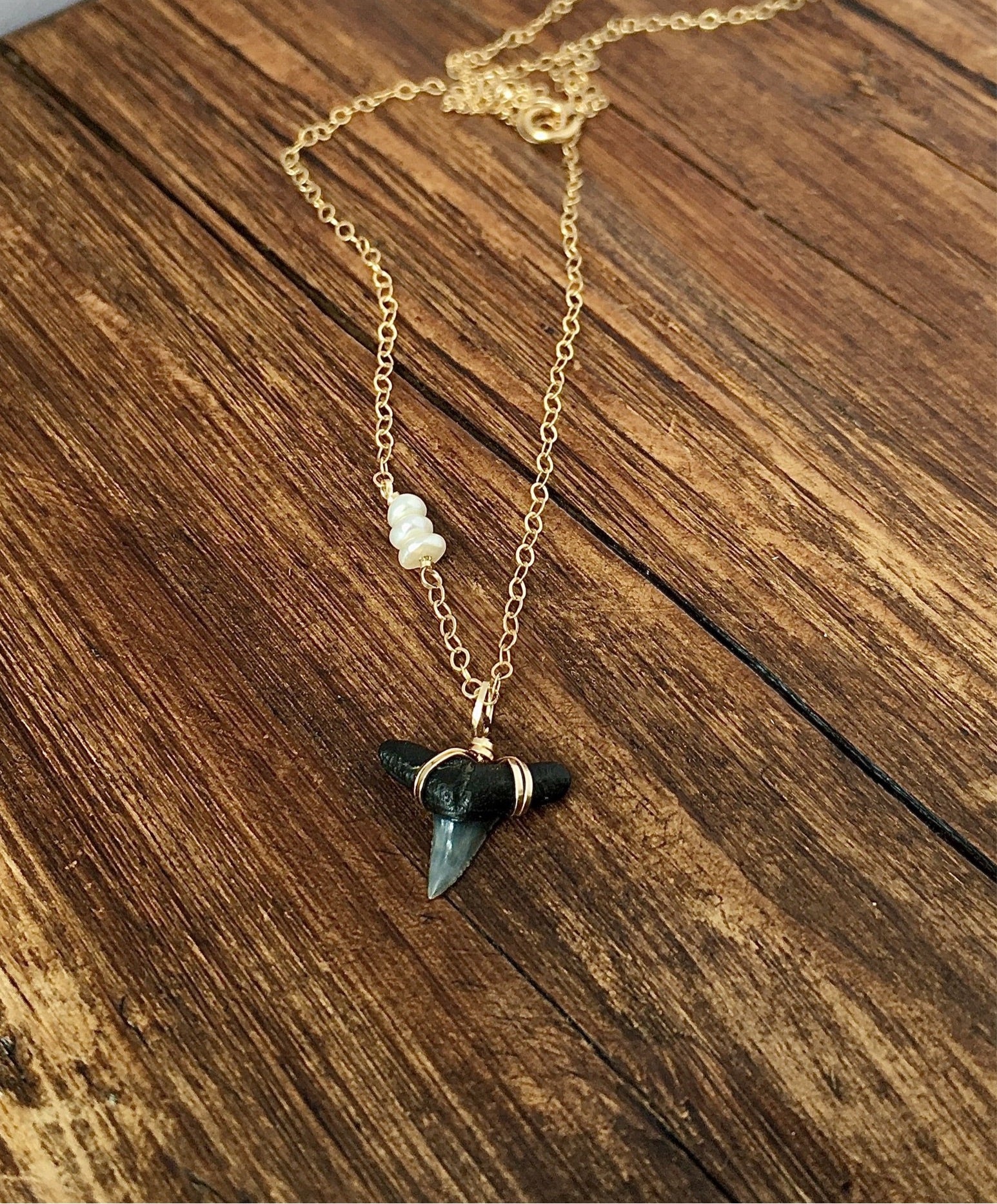 dainty gold wire wrapped shark tooth necklace with tiny pearls on driftwood—ethically sourced real fossilized shark tooth pendant—Foxy Fossils 